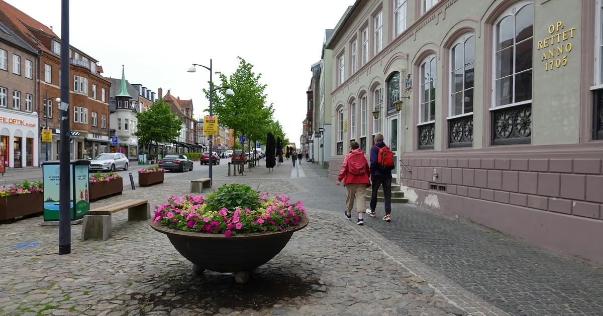 Gågate i en dansk småby med blomsterurne og folk som går