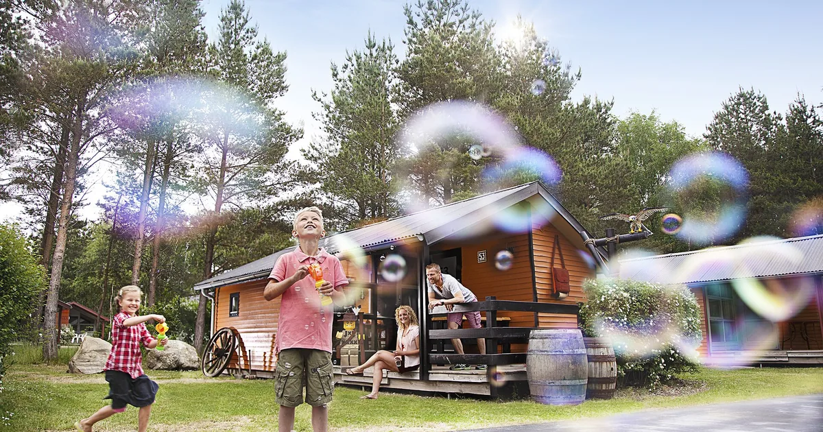 To barn som blåser såpebobler foran en tømmerhytte i Legoland Holiday Village