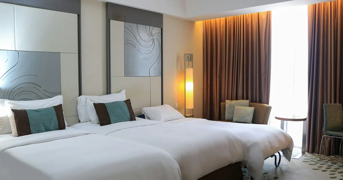 Hotellrom med to oppredde senger og lampe på nattbordet