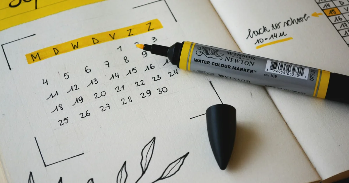 Håndtegnet kalender i en notatbok med en tusj ved siden av