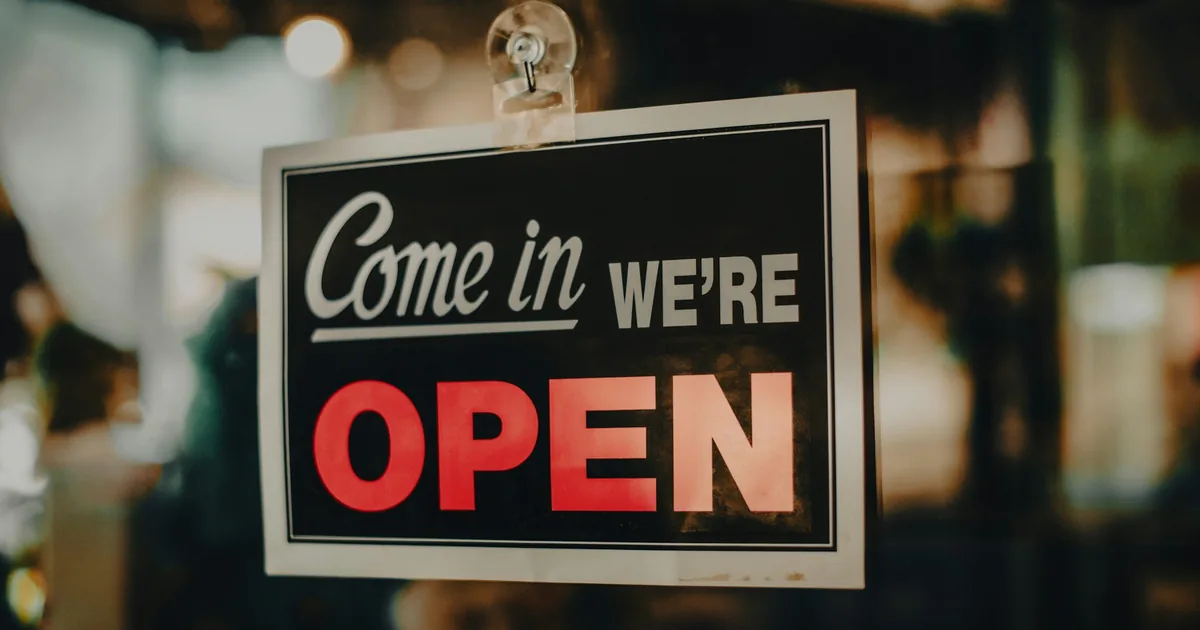 Skilt i en butikkdør med teksten «Come in, we're open»