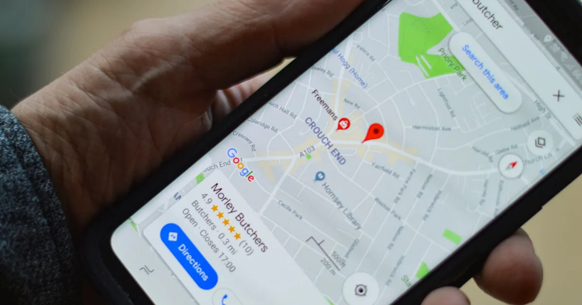 Hånd som holder en mobil med kart og veibeskrivelse på skjermen