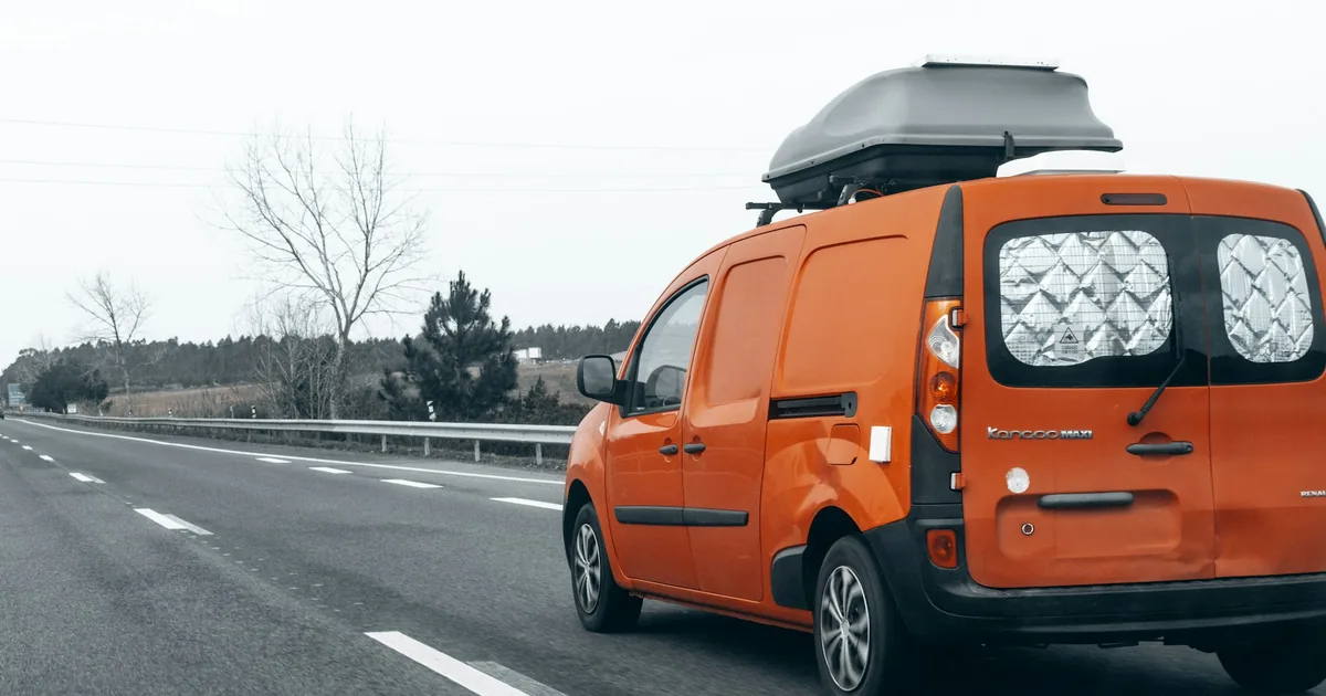 Oransje varebil med takboks på en motorvei