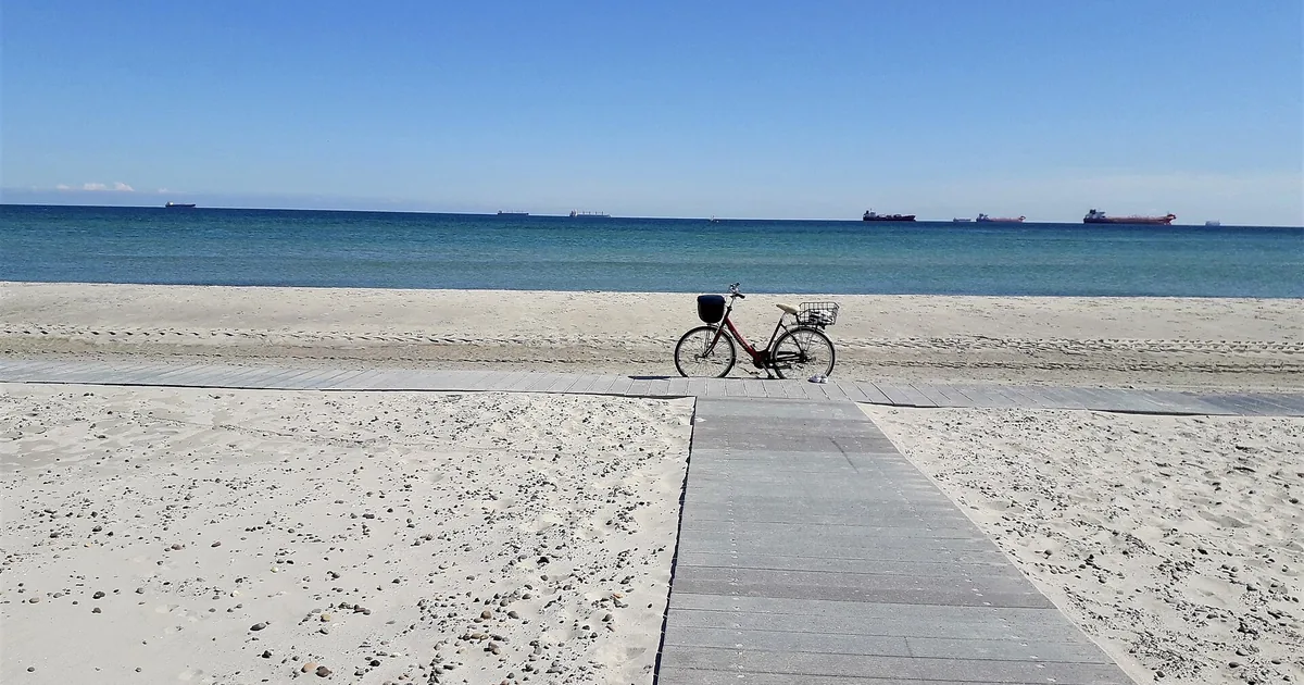 Sykkel på en bred sandstrand med havet i bakgrunnen