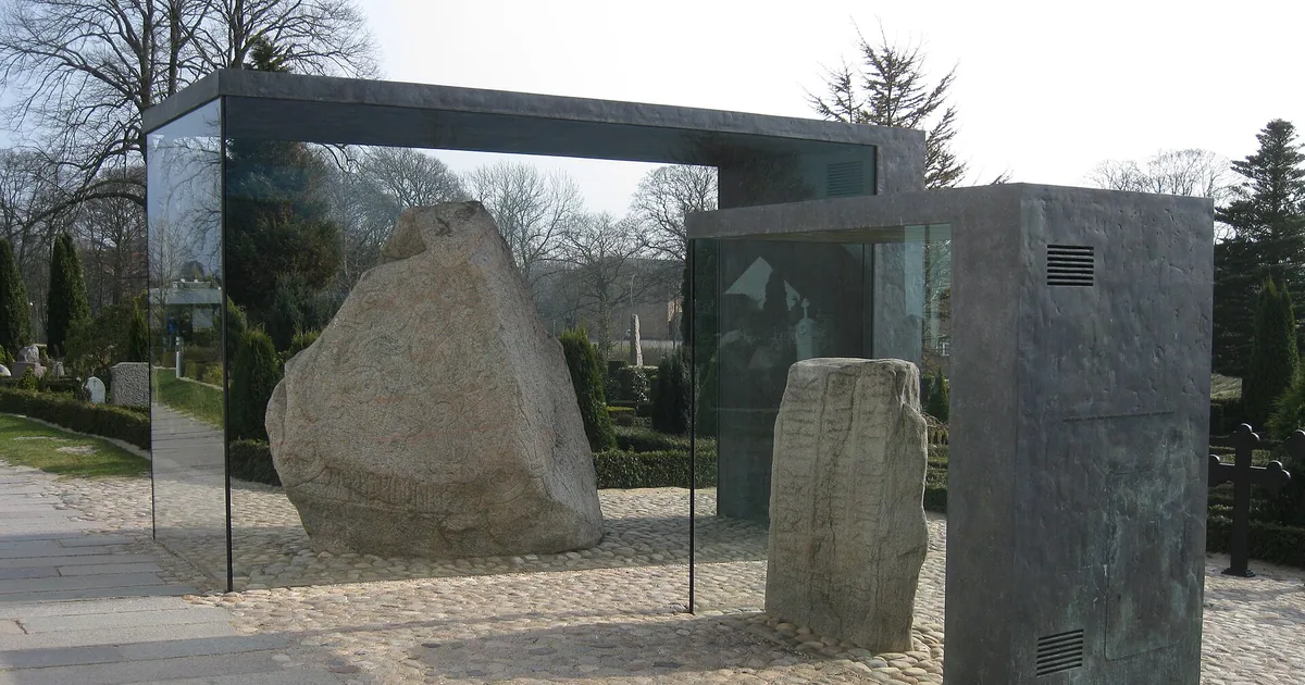 Jellingsteinene i glassmontrene sine på kirkegården i Jelling