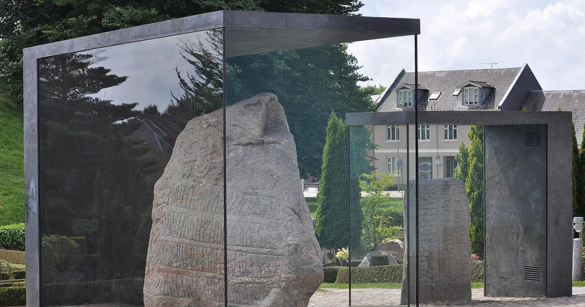 Den store Jellingsteinen med runeinnskrift, beskyttet av glass